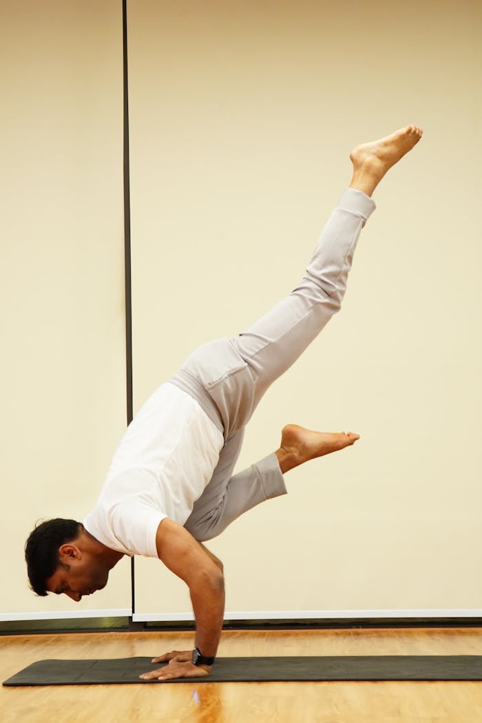 Adult man practicing yoga handstand indoors, showcasing balance and strength.